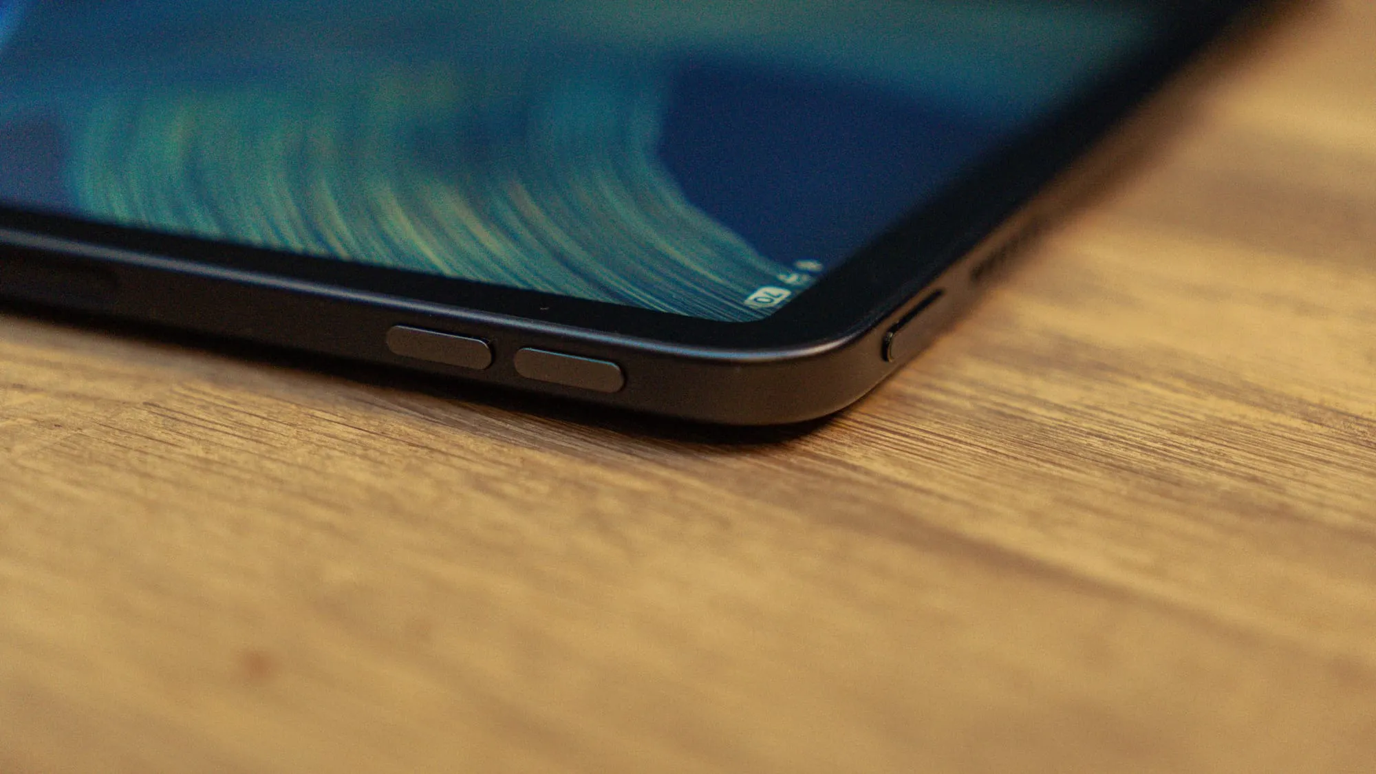Edge of the Alexa Tablet 12 Pro on a wooden table, with two buttons on the long side and one button on the short side